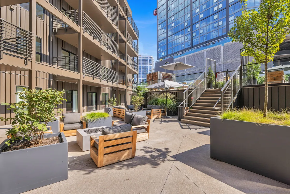A contemporary outdoor seating area with comfortable chairs, a staircase, and surrounding greenery, designed for relaxation, socializing, and group celebrations in an inviting open-air environment.
