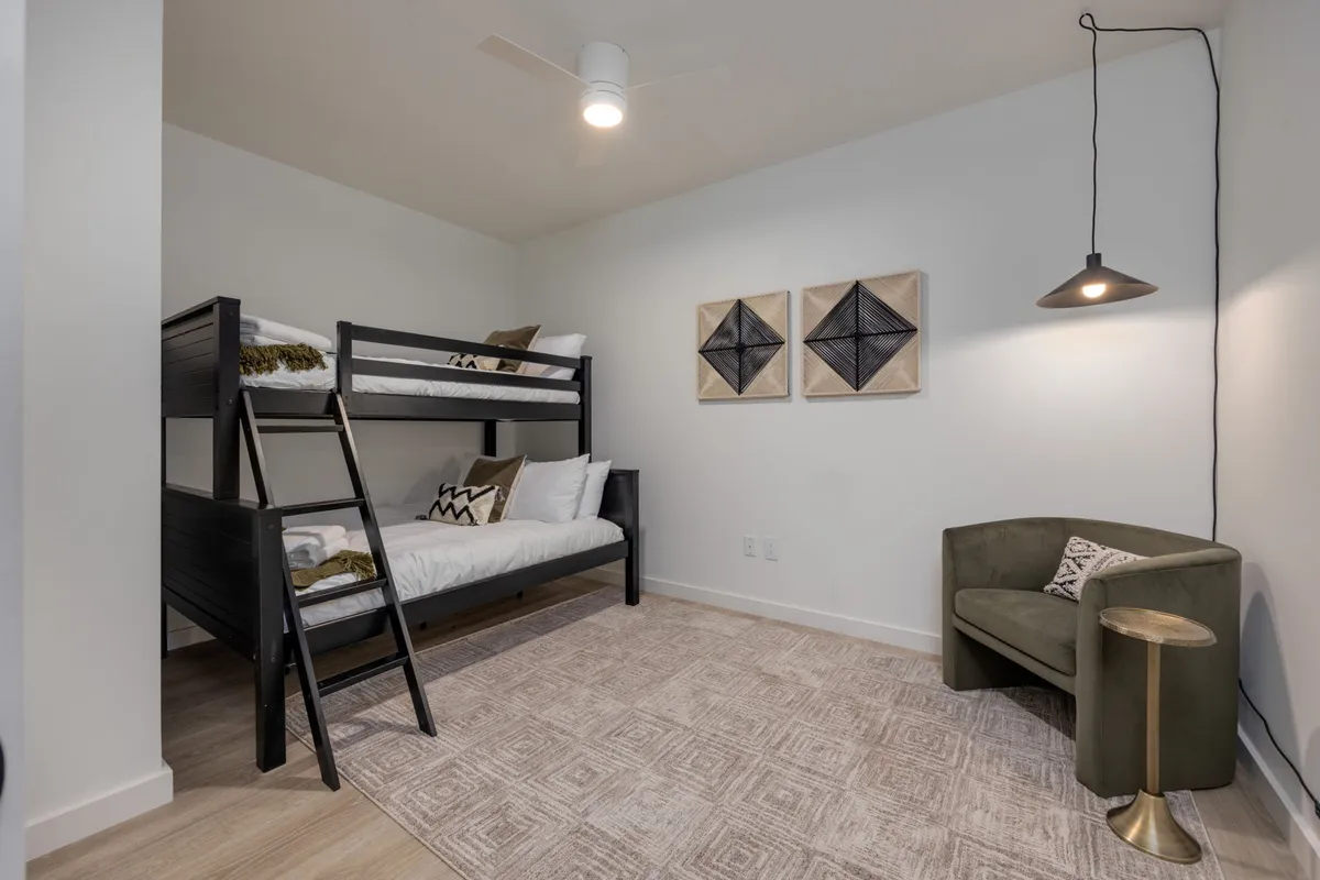 A casual bedroom with a twin-over-full bunk bed, a cozy armchair, and playful artwork on the wall. The space is inviting for families or groups, offering flexibility and comfort.