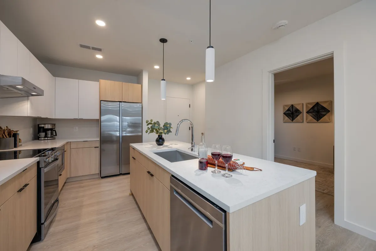 A contemporary kitchen space featuring a central island, stainless steel appliances, and elegant wine glasses with snacks displayed, creating a welcoming environment ideal for daily routines and guest entertainment.