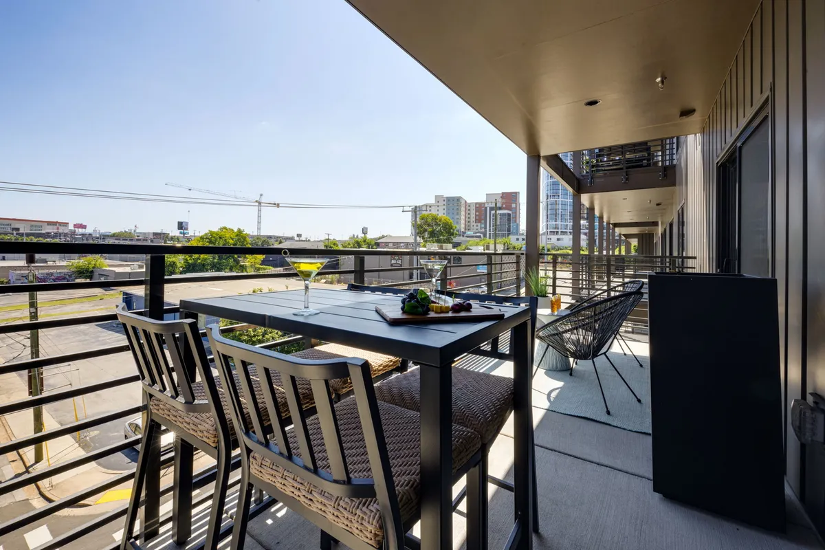 A private balcony set with a cozy dining area and seating, offering a sweeping view of the city skyline. The setting is perfect for enjoying morning coffee, alfresco meals, or unwinding with friends as the city buzzes below.