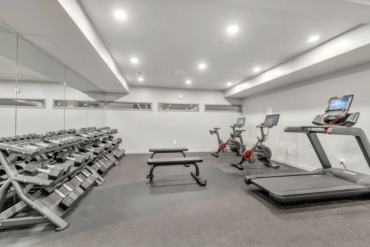 A well-equipped fitness center featuring a dumbbell rack, exercise bikes, and a treadmill. The space is bright and modern, conveying a health-conscious and active lifestyle for travelers.